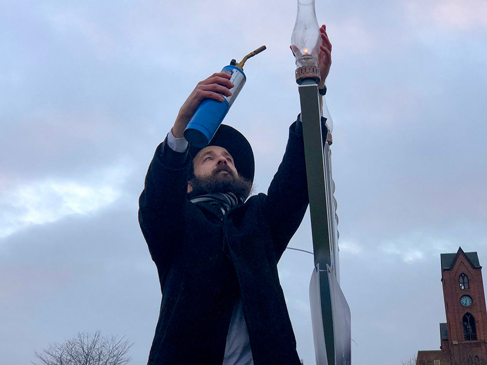 Rabbi Shmuel Serebryanski with a blow torch in hand, lights the first candle of Hanukkah.